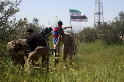 FILE - Free Syrian Army fighters prepare a Katyusha rocket launcher before firing in the al-Arbaeen mountain area of western Idlib, Syria, April 19, 2015.
