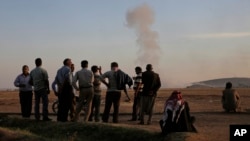 Turkish Kurds watch as airstrikes hit Kobani, inside Syria, as fighting intensifies between Syrian Kurds and the militants of Islamic State group, in Mursitpinar, on the outskirts of Suruc, at the Turkey-Syria border, Wednesday, Oct. 8, 2014.