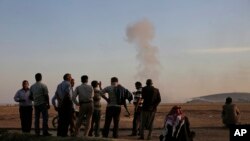 Turkish Kurds watch as airstrikes hit Kobani, inside Syria, as fighting intensifies between Syrian Kurds and the militants of Islamic State group, in Mursitpinar, on the outskirts of Suruc, at the Turkey-Syria border, Wednesday, Oct. 8, 2014.