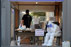 A health official wearing protective gear takes a rest during the COVID-19 testing at a public health center in Goyang, South Korea, May 28, 2020.