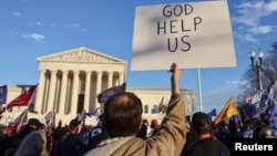 Arhiva: Čovjek drži parolu "Pomozi nam Bože tokom protesta zbog izbornih rezultata, ispred zgrade Vrhovnog suda SAD u Washingtonu, 12. decembra 2020.