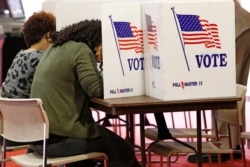 FILE - Voters work on their ballots in the kiosks in Jackson, Miss., March 10, 2020.