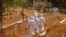 FILE - Health workers walk inside a new graveyard as they move bury people suspected of dying from the Ebola virus on the outskirts of Monrovia, Liberia, March 11, 2015. 
