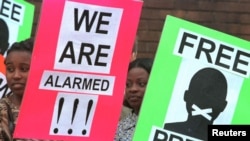 FILE - Protesters for press freedom hold placards outside the Harare Magistrate's Court in Zimbabwe on Feb. 9, 2020.