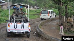 FILE - A Congolese girl gestures to passing peacekeepers, serving in the United Nations Organization Stabilization Mission in the Democratic Republic of the Congo (MONUSCO), as they ride on patrol in the town of Kiwanja, Democratic Republic of Congo, Oct. 19, 2018.