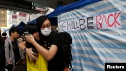 Pro-democracy supporters bid farewell to each other next to a banner that reads "We will be back" outside the government headquarters building at the financial district in Hong Kong, Dec. 11, 2014. 