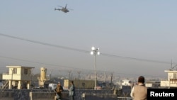 Afghan security forces keep watch as a NATO helicopter flies over at the site of an attack in Jalalabad December 2, 2012. Suicide attackers detonated bombs and fired rockets outside a major U.S. base in Afghanistan on Sunday, killing five people in a braz