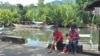 A woman and her neighbor chat while she sorts fish in this small fishing town along Ulugan Bay, which fronts the South China Sea, in Bahile, Palawan province, Philippines. (Photo: Simone Orendain for VOA)