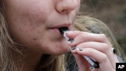 Seorang siswa SMU mengisap rokok elektrik dekat sekolahnya di Cambridge, Massachusetts, Amerika Serikat, 11 April 2018. (Foto: AP)