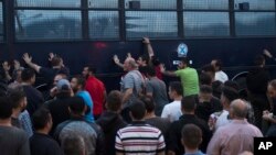 Protesters rock a riot police bus in the town of Mytilene on the northeastern Aegean island of Lesbos, May 3, 2018. 