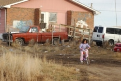 In this file photo, a young girl rides her bike on Pine Ridge Indian Reservation in southwestern S.D. on Tuesday , Jan. 10, 2006. At least 60% of Pine Ridge homes are substandard, lacking electricity, running water or sewage systems. (AP Photo...