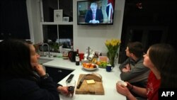 Una familia londinense escucha el mensaje del primer ministro Boris Johnson en el que anunció una cuarentena obligatoria en todo el país, siguiendo los pasos de Italia, España y Francia.