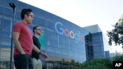 FILE - Two men walk past a building on the Google campus in Mountain View, California. 