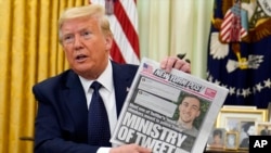 FILE - President Donald Trump holds up a copy of the New York Post as he speaks before signing an executive order aimed at curbing protections for social media giants, in the Oval Office of the White House, May 28, 2020.