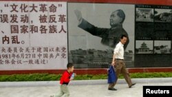 FILE - Visitors walk past a portrait of the late Chinese leader Mao Zedong at the Cultural Revolution Museum in Shantou in China's southern Guangdong province, May 15, 2006.
