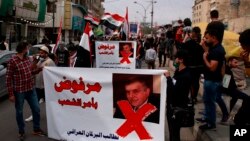 Protesters hold posters showing Iraq's Prime Minister-designate Mohammed Tawfiq Allawi with Arabic that reads, "Rejected by order of the people," during a rally in Baghdad, Iraq, March 1, 2020.