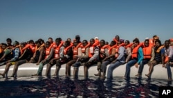 FILE - Refugees and migrants from Eritrea, Mali, Bangladesh and other countries wait on board a dinghy to be rescued in the Mediterranean Sea, 27 kilometers (17 miles) north of Sabratha, Libya, July 19, 2016.