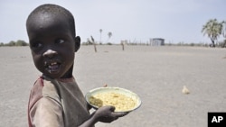A young boy walks away with his food from a government sponsored feeding center in central Turkana, Kenya, August 30, 2011