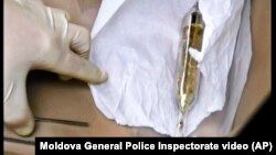 An investigator with the Moldova General Police Inspectorate looks at a vial containing cesium-135 on the driver's seat of Valentin Grossu's car following his arrest in Chisinau, Moldova, Feb. 19, 2015.
