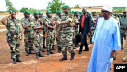 Mali's President Ibrahim Boubacar Keita, right, reviews troops in Kati, near Bamako, after visiting soldiers injured in an attack on their camp in northern Mali earlier in the week that left 11 other soldiers dead, Aug. 6, 2015.