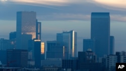 FILE - Pollution obscures the skyline of downtown as the sun rises over Denver, Feb. 28, 2019.