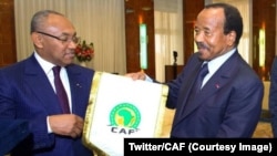 Le président de la Confédération africaine du football, Ahmad, et le président du Cameroun, Paul Biya, tiennent un fanion de la CAN, sur une photo publiée le 3 octobre 2018. (Twitter/CAF) 