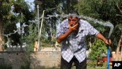 FILE - An Iraqi man cools himself with water in central Baghdad, Iraq, July 16, 2015. 