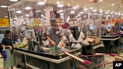 Sejumlah kasir di sebuah supermarket di mal AEON, Tangerang, melayani pembeli di balik pembatas lapisan plastik untuk mencegah penularan virus corona, 22 Mei 2020. (Foto: AP)