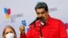El presidente de Venezuela, Nicolás Maduro, sostiene una pequeña Constitución venezolana mientras hace comentarios junto a su esposa, Cilia Flores, luego de votar durante las elecciones regionales, en Caracas, el 21 de noviembre de 2021.