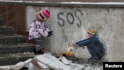 Anastasia, 4, stands next to an artwork of the famous street artist Tvboy in the town centre, amid Russia's attack on Ukraine, in Bucha, outside Kyiv, Ukraine Jan. 29, 2023.