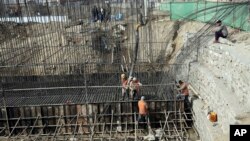 FILE - In this Feb. 10, 2020 photo, Afghan laborers work on a bridge project funded by the government, in Kabul, Afghanistan. 