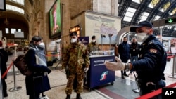 FILE - Police officers and soldiers check passengers leaving from Milan main train station, March 9, 2020. 