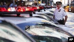 FILE - A police officer stands in a row of police cars parked in Times Square in New York.