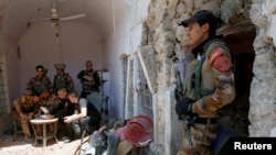 Seorang serdadu berjaga-jaga saat beberapa perwira dari unit kontraterorisme Irak menonton video yang dipancarkan dari drone dalam sebuah rapat dengan pasukan Irak di garis depan di Kota Tua Mosul Barat, Irak, 27 Juni 2017 (foto: REUTERS/Erik De Castro)