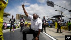 A NASCAR official kneels during the national anthem before a NASCAR Cup Series auto race at Atlanta Motor Speedway on Sunday, June 7, 2020, in Hampton, Ga.