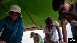 Students and a chaperone from Lich-Wilmerding High School in San Francisco sand desks for a school they helped build in the village of Guedj Martin, Senegal. (Annika Hammerschlag, for VOA)