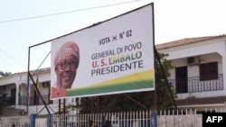 Deux hommes se tiennent devant un panneau du candidat présidentiel de l'opposition Umaro Sissoco Embalo à Bissau, le 27 décembre 2019, à l'approche du second tour des élections présidentielles. (AFP)