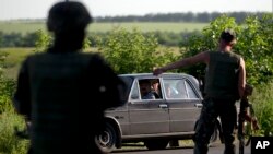 Ukrainian soldiers stop a vehicle at a checkpoint outside the town of Amvrosiivka, eastern Ukraine, close to the Russian border, June 5, 2014.