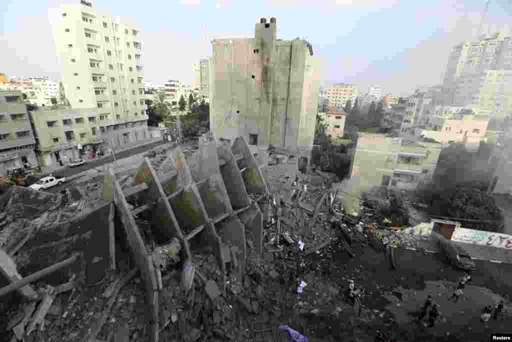 Palestinians gather around the remains of an apartment building which was destroyed by an air strike in Gaza City, Aug. 26, 2014.