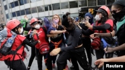 Members of NGO Independent Space Marabunta (Espacio Libre Independiente Marabunta) try to stop a fight among protesters during a march demanding justice for the victims of gender violence and femicides in Mexico City, Mexico, Aug. 16, 2020. 