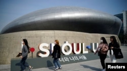 FILE - People wearing masks to protect against contracting the coronavirus disease (COVID-19) walk along a street in Seoul, South Korea, March 25, 2020. 