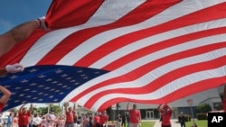 FILE - Participants carry an American flag during the 4th of July parade in Santa Monica, California, on July 4, 2017. 