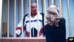 FILE - Sergei Skripal is seen behind bars on a screen of a monitor outside a courtroom in Moscow, Aug. 9, 2006.
