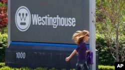FILE - A woman walks past the sign marking the entrance to the Westinghouse International Headquarters on May 19, 2014, in Cranberry, Pa.