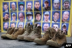 Soldiers' boots sit in front of a poster with portraits of missing Ukrainian servicemen at Independence Square in Kyiv on Oct. 16, 2024. Relatives of the missing held a rally to demand that Ukrainian authorities speed up the search for their loved ones.