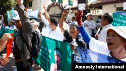 Protesters raise clenched fists with banners printed with detained activist Vorn Pao in front of the Appeals Court during a rally in Phnom Penh, Cambodia, March 24, 2014.