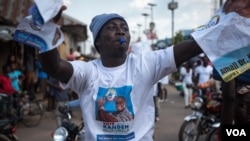 A supporter of the National Grand Coalition waves campaign posters during a rally in Bo, Sierra Leone, on March 4, 2018. (J. Patinkin/VOA)