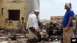星期一，在也门南部城市亚丁，亲政府的武装人员聚集在自杀式汽车炸弹爆炸现场。（2016年8月29日）