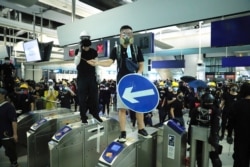 Demonstrators stand on turnstiles during a protest at the Yuen Long MTR station in Hong Kong, Aug. 21, 2019.