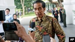 New Indonesian President Joko Widodo, center, talks to the media at Merdeka Palace in Jakarta, Indonesia, Oct. 21, 2014.